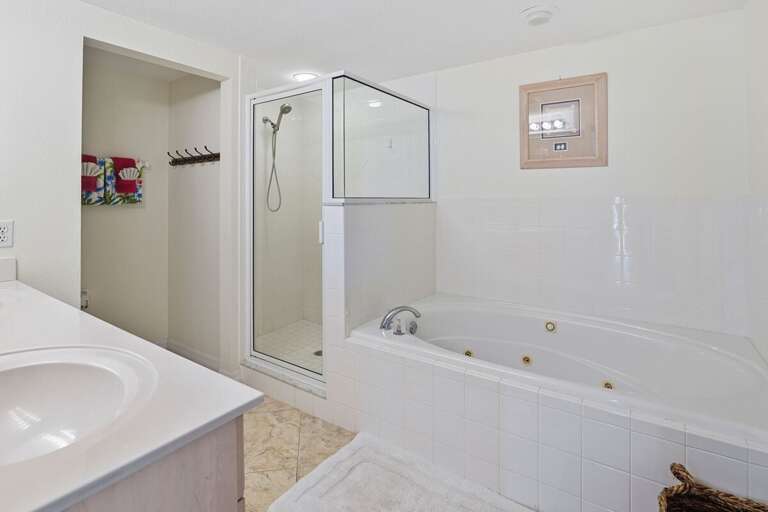Unwind after a day at the beach in this spa-like bathroom featuring a jetted soaking tub, walk-in shower, and dual vanity sinks—perfect for relaxation during your coastal getaway.