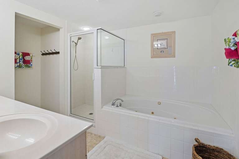 Unwind after a day at the beach in this spacious bathroom featuring a jetted soaking tub, walk-in shower, and fresh coastal touches for the perfect seaside retreat.