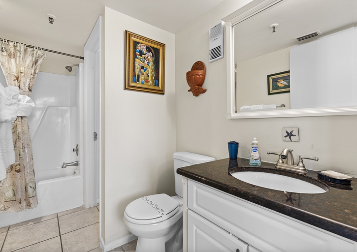 Freshen up after a day at the beach in this clean, bright bathroom featuring a shower/tub combo, modern vanity, and coastal touches—perfect for your relaxing beach stay.