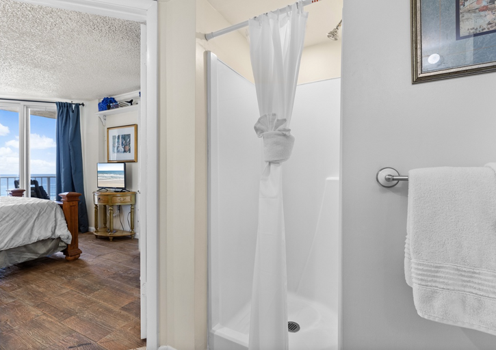 The master bath features a convenient walk-in shower, fresh linens, and direct access to the ocean-view bedroom—providing comfort and ease during your beach stay.