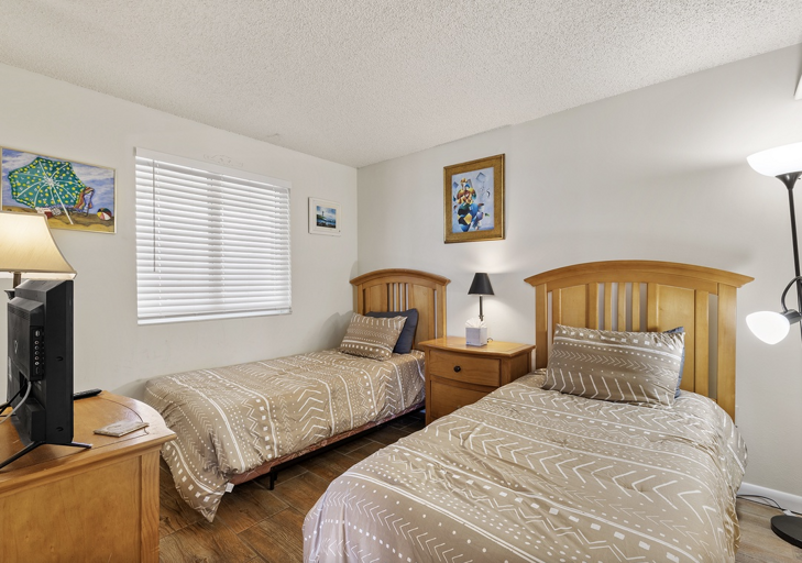 Perfect for families, this guest bedroom offers two comfortable twin beds, a TV, and warm decor. A great retreat for kids or friends to relax and recharge during your beach stay.