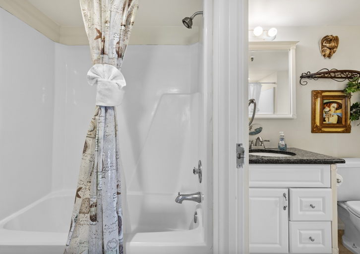 Refresh after your beach adventures in this clean bathroom featuring a shower/tub combo, modern vanity, and bright coastal décor—ideal for comfort and convenience during your beach stay.