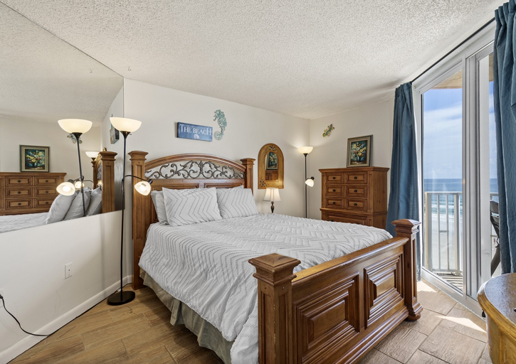 Wake up to ocean views in this spacious master bedroom featuring a king bed, elegant furnishings, and private balcony access—perfect for a restful and luxurious beach stay.
