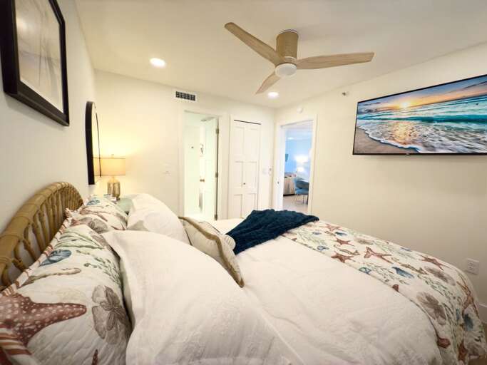 Cozy up in this inviting guest room featuring a beach-themed quilt, flat-screen TV, and warm décor—perfect for a restful night's sleep after enjoying the sun, surf, and sand.
