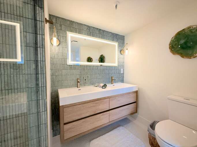 Refresh after a day at the beach in this elegant bathroom featuring a spacious glass shower, dual vanity, and sleek coastal décor—designed for style and relaxation.