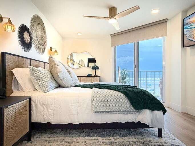 Wake up to breathtaking beach views in this stylish primary bedroom featuring modern décor, cozy bedding, and balcony access—perfect for a serene seaside escape.