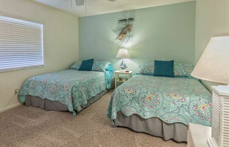 This charming guest bedroom features two cozy double beds with beach-inspired décor, perfect for families or friends to relax after a fun-filled day by the ocean.