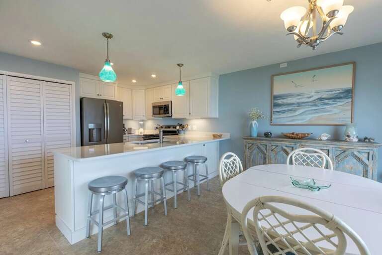 Enjoy a bright, beach-inspired kitchen and dining area with modern appliances, seating for the whole family, and coastal décor—perfect for gathering after a day of sun and surf. Enjoy a bright, beach-inspired kitchen and dining area with modern appliances, seating for the whole family, and coastal décor—perfect for gathering after a day of sun and surf.