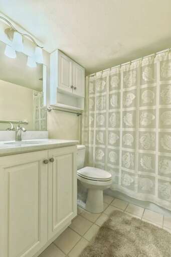 This inviting bathroom features a bright vanity, coastal-themed shower curtain, and fresh design—perfect for refreshing after a relaxing beach day at your vacation rental.