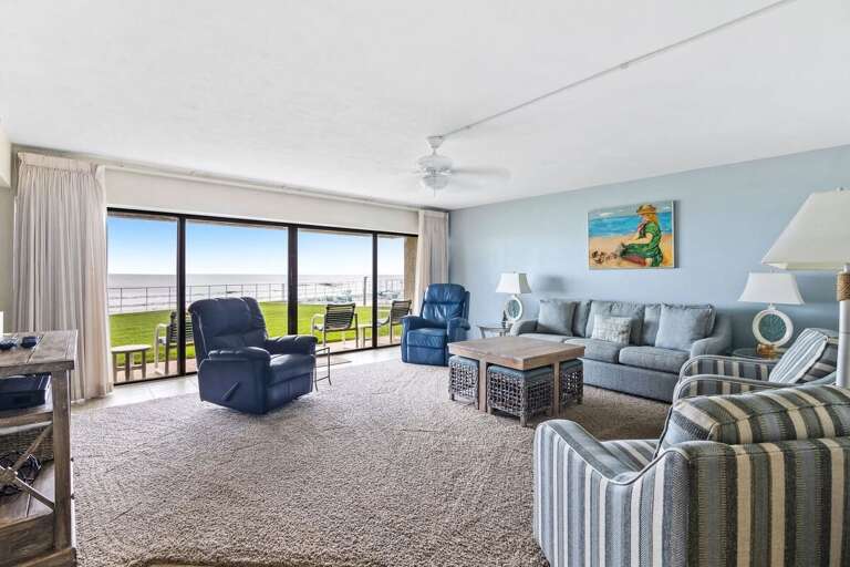 Unwind in a spacious, beach-inspired living room with plush seating and stunning ocean views right outside the sliding doors—perfect for a relaxing beach stay with family or friends.