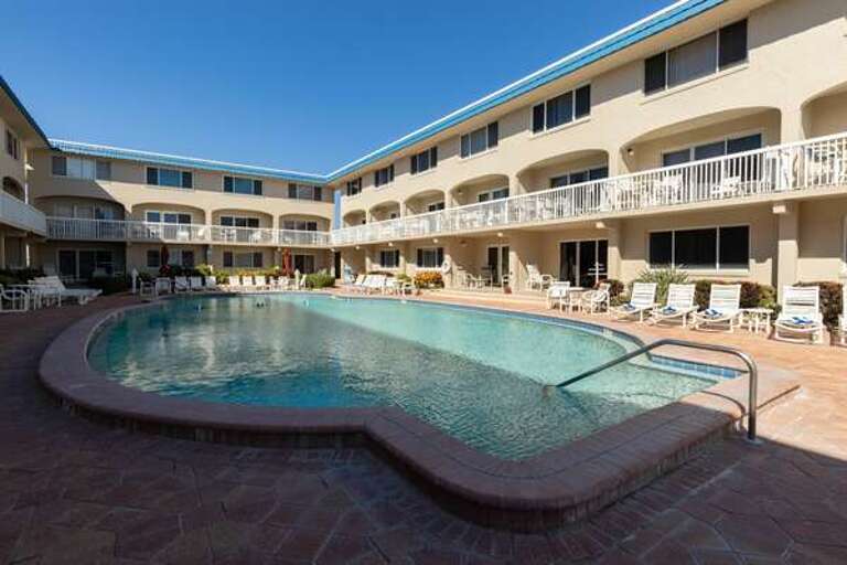 Cool off in the sparkling pool at this beachside condo complex, surrounded by lounge chairs and easy access to the sand—perfect for relaxing and enjoying your beach vacation stay. Cool off in the sparkling pool at this beachside condo complex, surrounded by lounge chairs and easy access to the sand—perfect for relaxing and enjoying your beach vacation stay.
