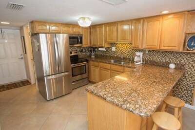 Enjoy a spacious kitchen with granite countertops, stainless steel appliances, and plenty of seating—perfect for preparing meals and gathering during your beach vacation stay.