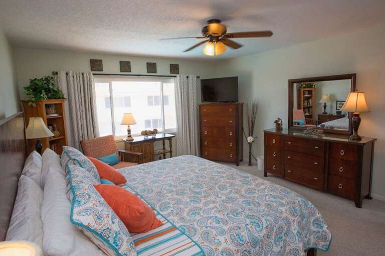 Unwind in this bright and cozy bedroom featuring a king bed, stylish coastal bedding, TV, and plenty of storage—perfect for relaxing after a sun-filled day at the beach. Unwind in this bright and cozy bedroom featuring a king bed, stylish coastal bedding, TV, and plenty of storage—perfect for relaxing after a sun-filled day at the beach.