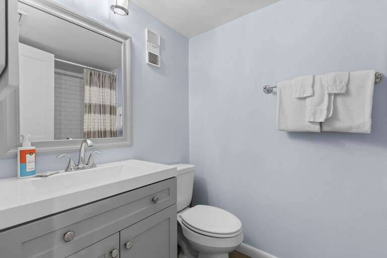 Enjoy this bright and refreshing beach-inspired bathroom featuring a sleek vanity, soft towels, and calming coastal tones—perfect for freshening up after a day in the sun and surf.