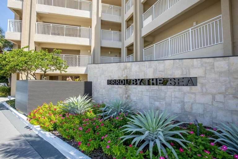 Begin your beach stay at Errol by the Sea with this inviting entrance surrounded by lush landscaping. A perfect start to your coastal getaway, just steps from the sand and surf.