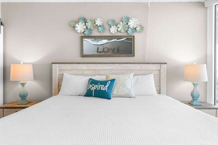 Cozy beach-inspired bedroom featuring a king bed, coastal décor, and soothing tones—perfect for relaxing after a day enjoying the sand, sun, and surf.