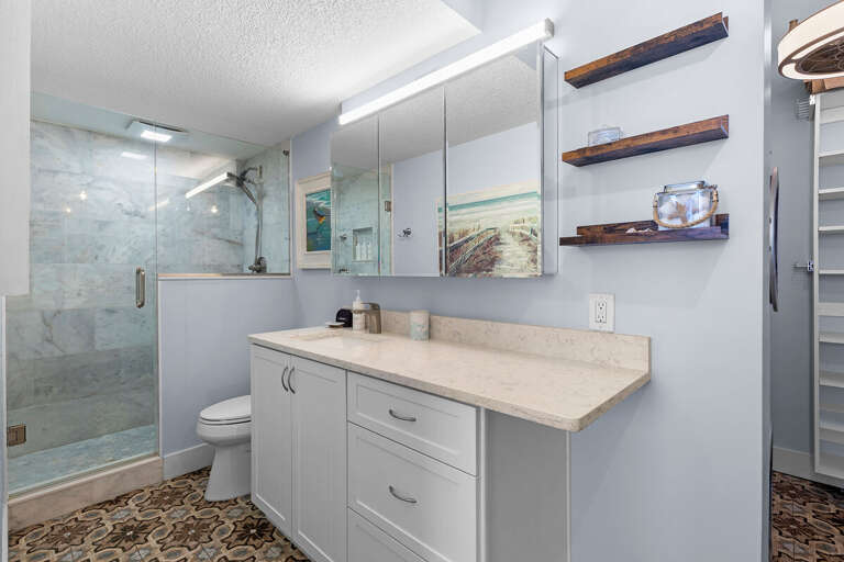 Elegant beach-inspired bathroom featuring a walk-in glass shower, spacious vanity, and coastal décor—offering a refreshing space to unwind after your seaside adventures.
