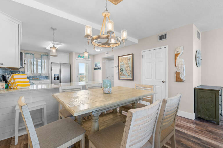 Gather for meals in this inviting beach-inspired dining area featuring coastal décor, warm lighting, and easy access to the kitchen—perfect for relaxed seaside living.