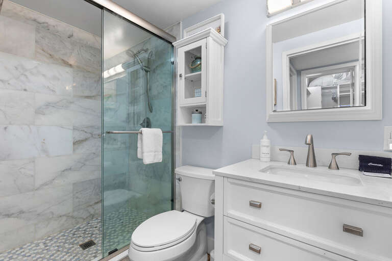 Modern beach-style bathroom featuring a sleek glass shower, bright vanity, and calming coastal tones—perfect for refreshing after a day at the shore.