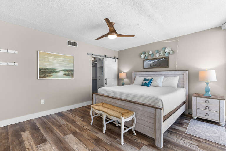 Relax in this spacious beachside bedroom featuring a king bed, calming coastal décor, and a stylish barn door—your perfect retreat after a day of seaside adventures.