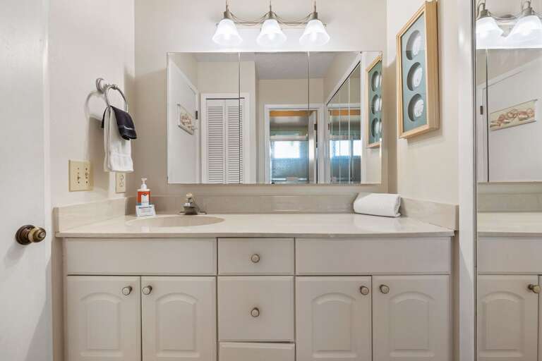 Freshen up after your beach adventures in this spacious master bathroom featuring a large vanity, bright lighting, and seaside-inspired décor for a relaxing coastal retreat.