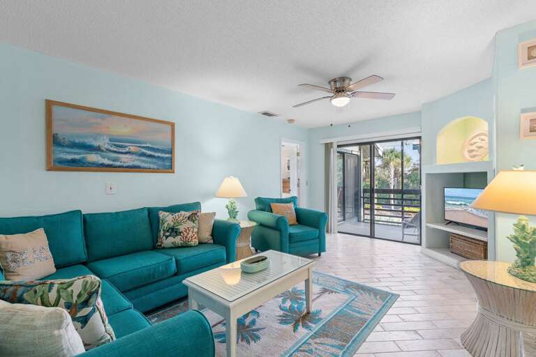 Relax in this bright, beach-themed living room featuring plush seating, coastal décor, and sliding