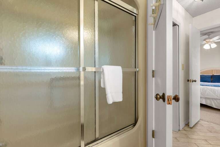 Rinse off after a sunny beach day in this clean, inviting bathroom featuring a glass-enclosed shower, soft towels, and coastal touches for a relaxing seaside retreat.