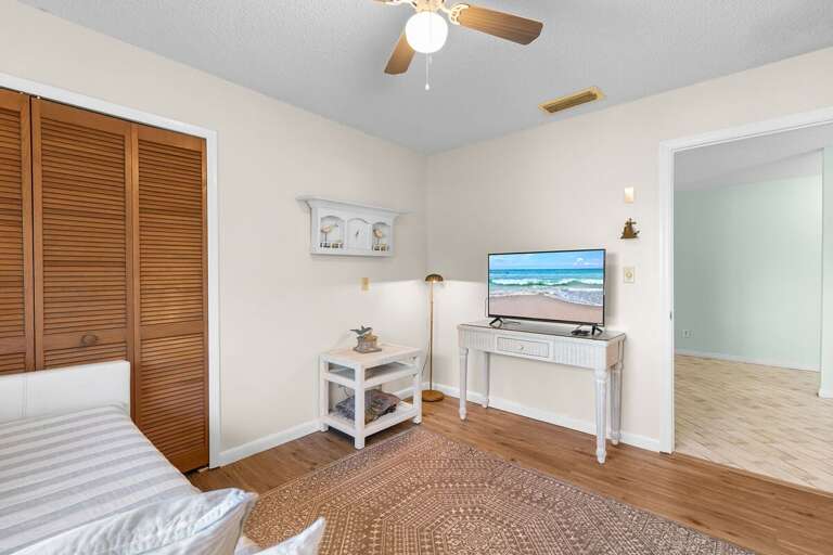 Unwind in this cozy beach-inspired guest room featuring a daybed, flat-screen TV, and warm coastal décor — a peaceful retreat after a day enjoying the sun and surf.