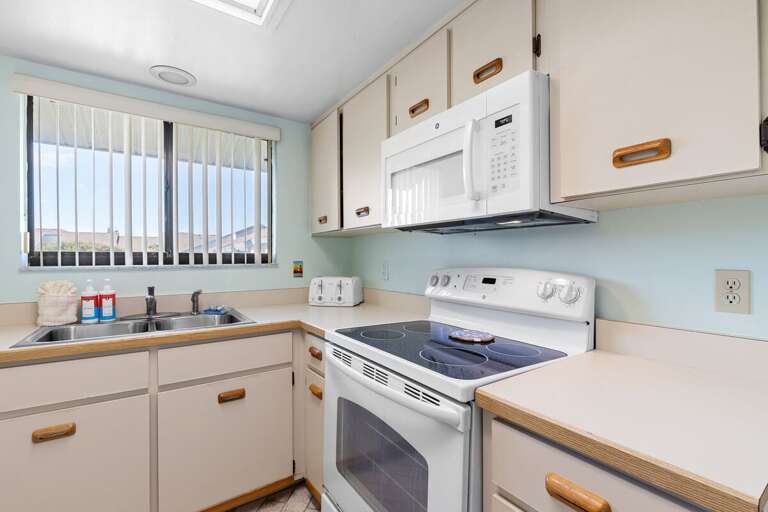 Whip up seaside meals in this bright, fully equipped kitchen featuring modern appliances, plenty of counter space, and natural light — perfect for your relaxing beach stay.