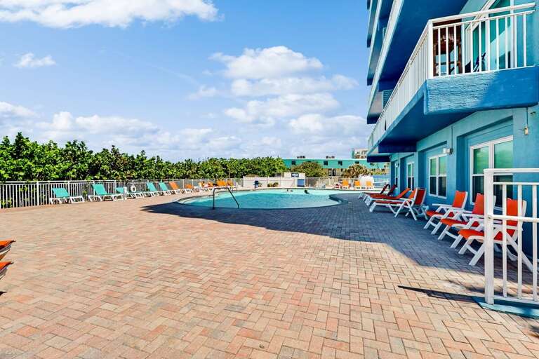 Blue Building Beside Breezy Beachside Pool, Brick Patio Scattered With Sun-loungers