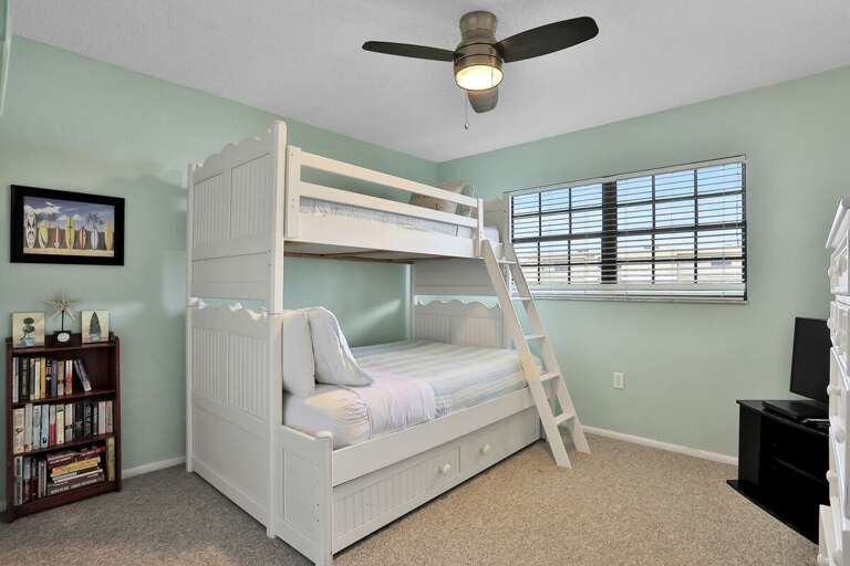 Bright Bedroom With Bunk Beds, Ceiling Fan, And Bookshelf In A Vacation Rental