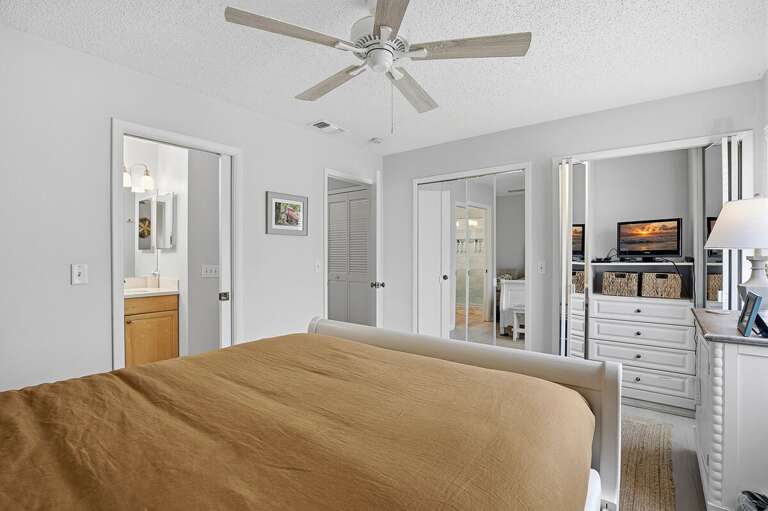 Bright beach stay bedroom featuring a comfortable bed, mirrored closet space, and easy access to the bathroom. A relaxing and functional retreat perfect for your coastal getaway near the beach.