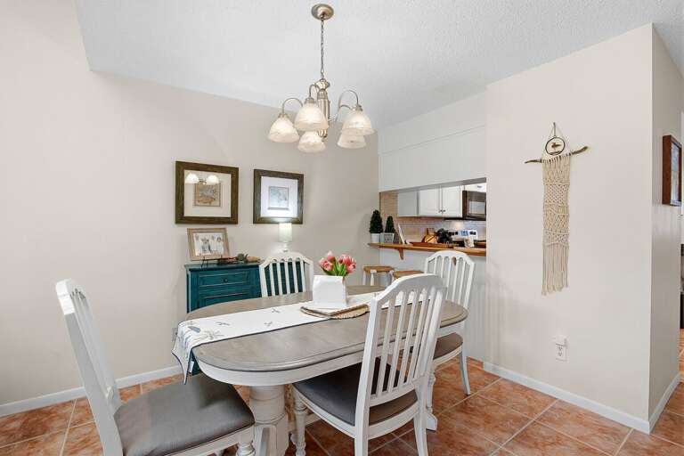 Charming beach stay dining space with coastal decor, ample seating, and easy access to the kitchen. Bright and inviting, it's perfect for enjoying meals together after a relaxing day at the beach.