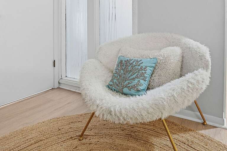 Charming beach stay seating nook with a plush accent chair and coastal-inspired decor. A perfect little spot to relax, read, or unwind during your peaceful beach getaway.