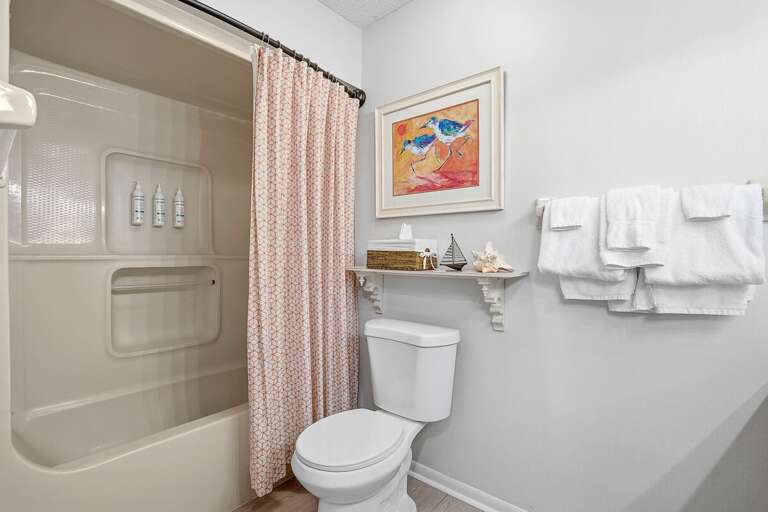 Clean and inviting beach stay bathroom featuring a shower/tub combo, fresh towels, and coastal decor accents. A comfortable and convenient space to refresh after a relaxing day at the beach.