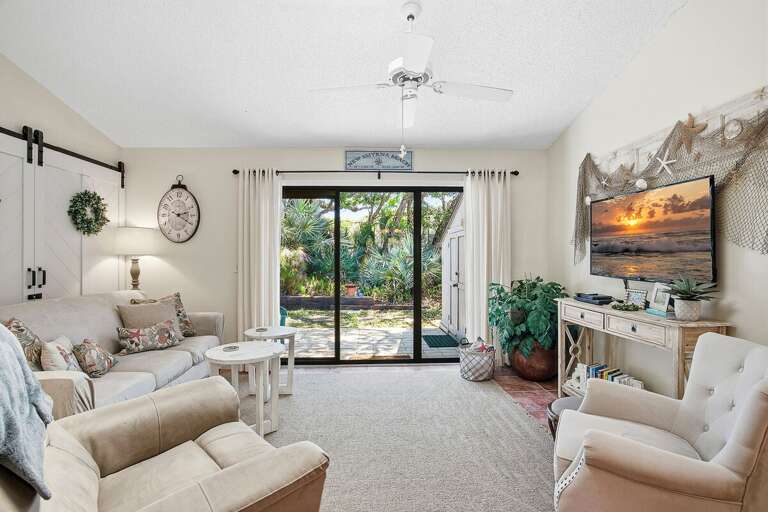 Spacious beach stay living room with comfortable seating, coastal decor, and large sliding doors