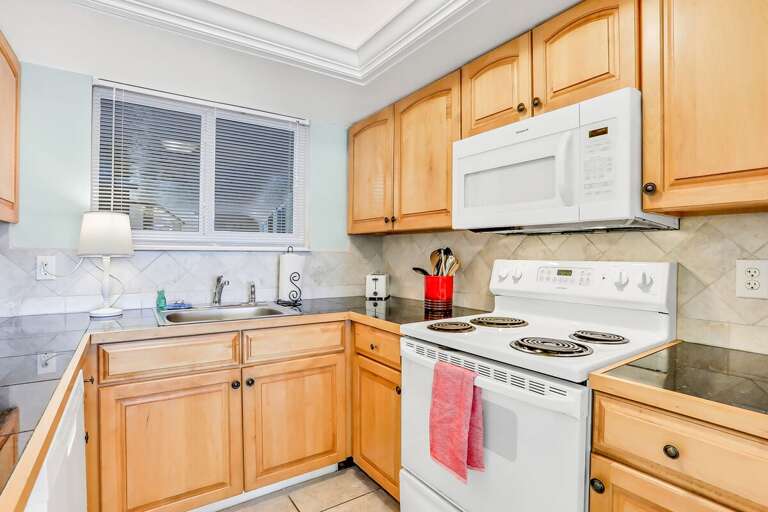 Bright, Basic Kitchen With Wooden Cabinets And White Appliances