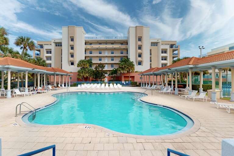 Palm-flanked Pool Facing A Multi-storey Building Under Blue Skies