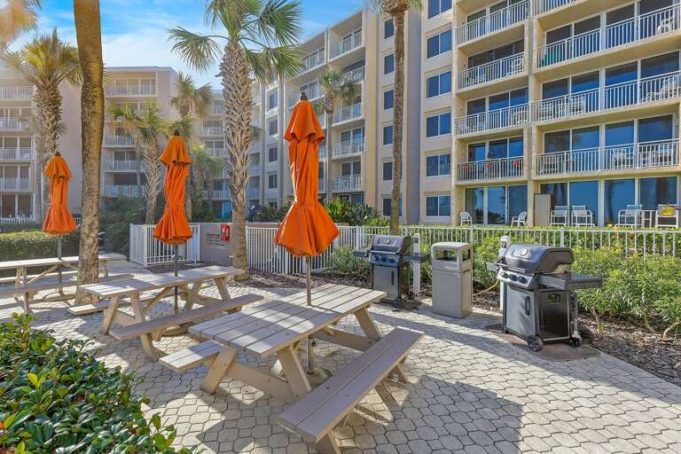 Enjoy outdoor dining during your beach stay with convenient gas grills, picnic tables, and shaded seating surrounded by tropical palms—perfect for a casual cookout after a day at the beach.