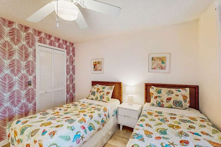 Vacation Rental Bedroom Featuring Patterned Bedding And Pink Curtains