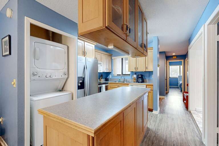 Blue-hued Kitchen With Wooden Cabinets And Laundry
