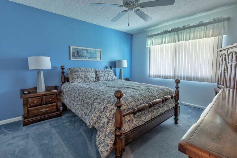 Drift into relaxation in this bright, beach-inspired bedroom featuring ocean-hued walls, cozy bedding, and classic coastal furnishings—perfect for unwinding after a day by the shore.