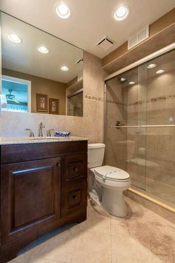 Refresh after your beach adventures in this elegant bathroom featuring a walk-in glass shower, granite vanity, and warm coastal tones—perfect for relaxing during your beach stay.