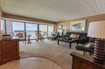 Relax in this spacious beachfront living room featuring floor-to-ceiling ocean views, cozy seating,