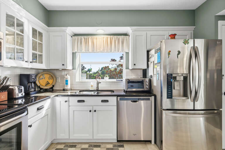 Bright kitchen with stainless steel appliances, ample counter space, and a sunny window view.