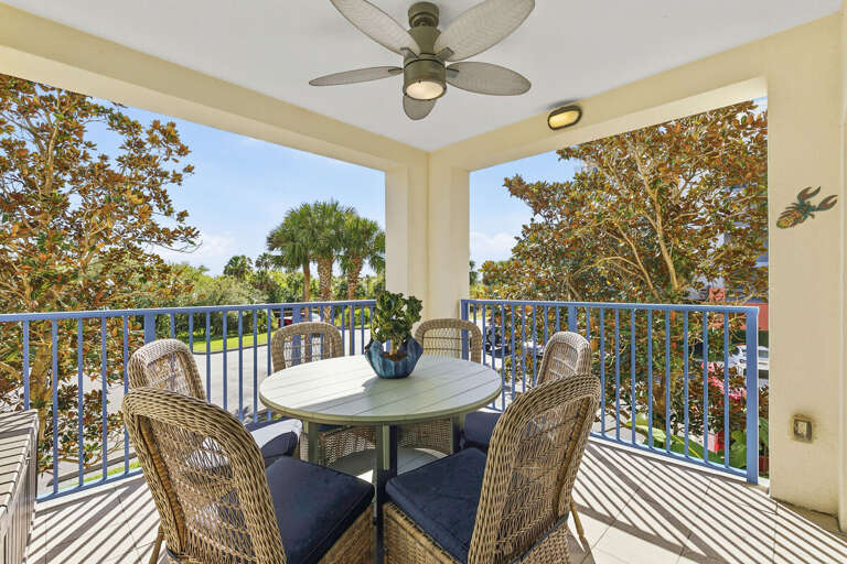 Enjoy outdoor dining on this covered balcony with comfortable seating and lush palm views. A perfect spot to relax, sip coffee, or unwind after a day at the beach during your coastal beach stay.