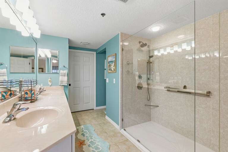 Refresh in this bright, coastal bathroom featuring a spacious walk-in glass shower, dual sinks, and