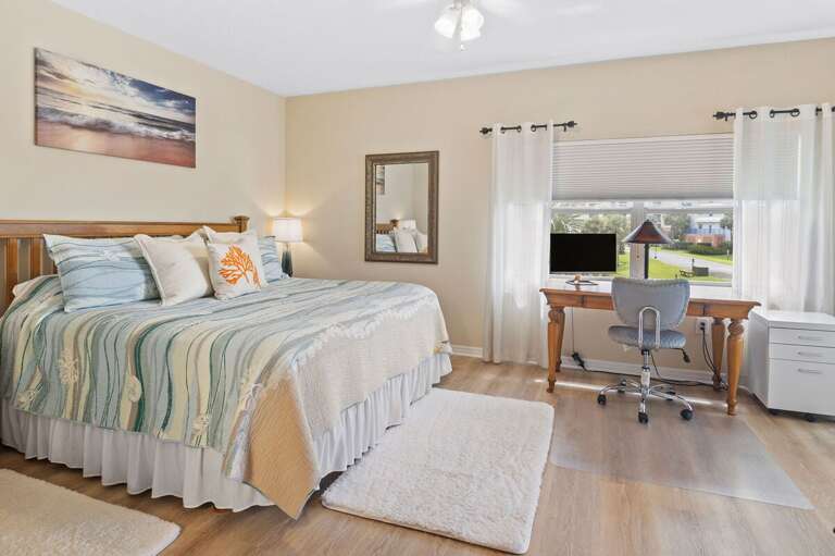 Relax in this airy coastal bedroom featuring a plush bed, soft linens, and a convenient workspace. A peaceful retreat to recharge after sun-soaked adventures during your unforgettable beach stay.
