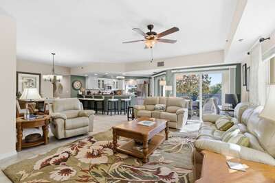 Spacious, sunlit living room with cozy seating, open kitchen, and private balcony—perfect for your