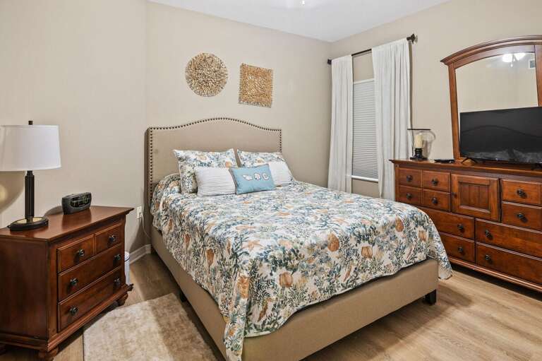 Unwind in this inviting primary bedroom featuring a plush bed, warm wood furnishings, and